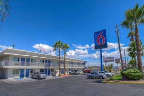 A motel with a large blue sign, a parking lot, and a Love Store sign in the background. - 1 Queen Bed | Smoking (Las Vegas NV)