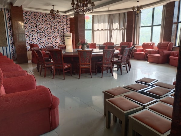 Un comedor con una mesa redonda rodeada de sillas, una pared con diseño y un ventanal con cortinas.