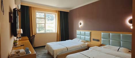 A hotel room with two beds, a desk with a lamp, a TV, and a window with curtains.