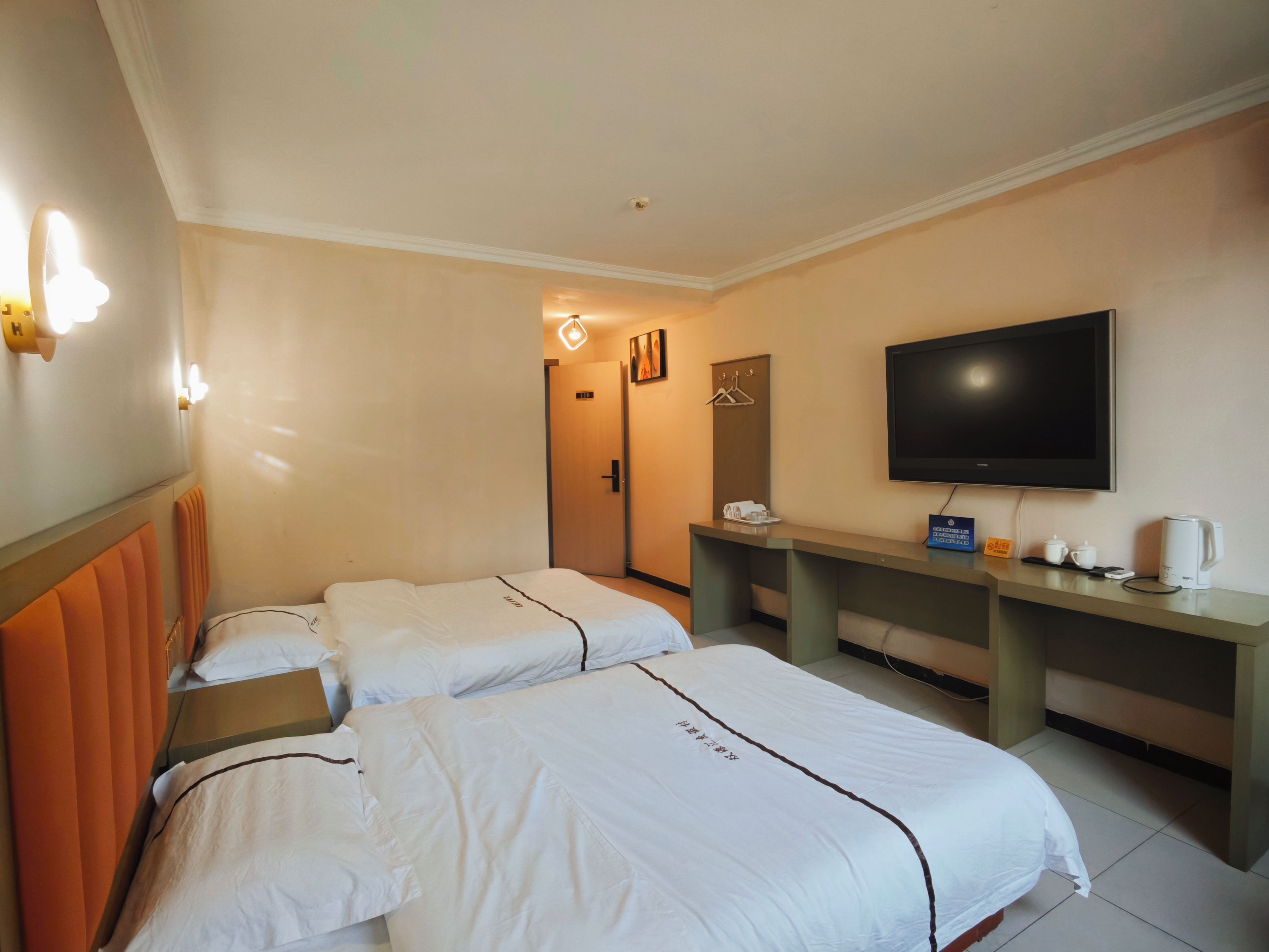 A hotel room with two beds, a desk, a television, and a coffee maker.