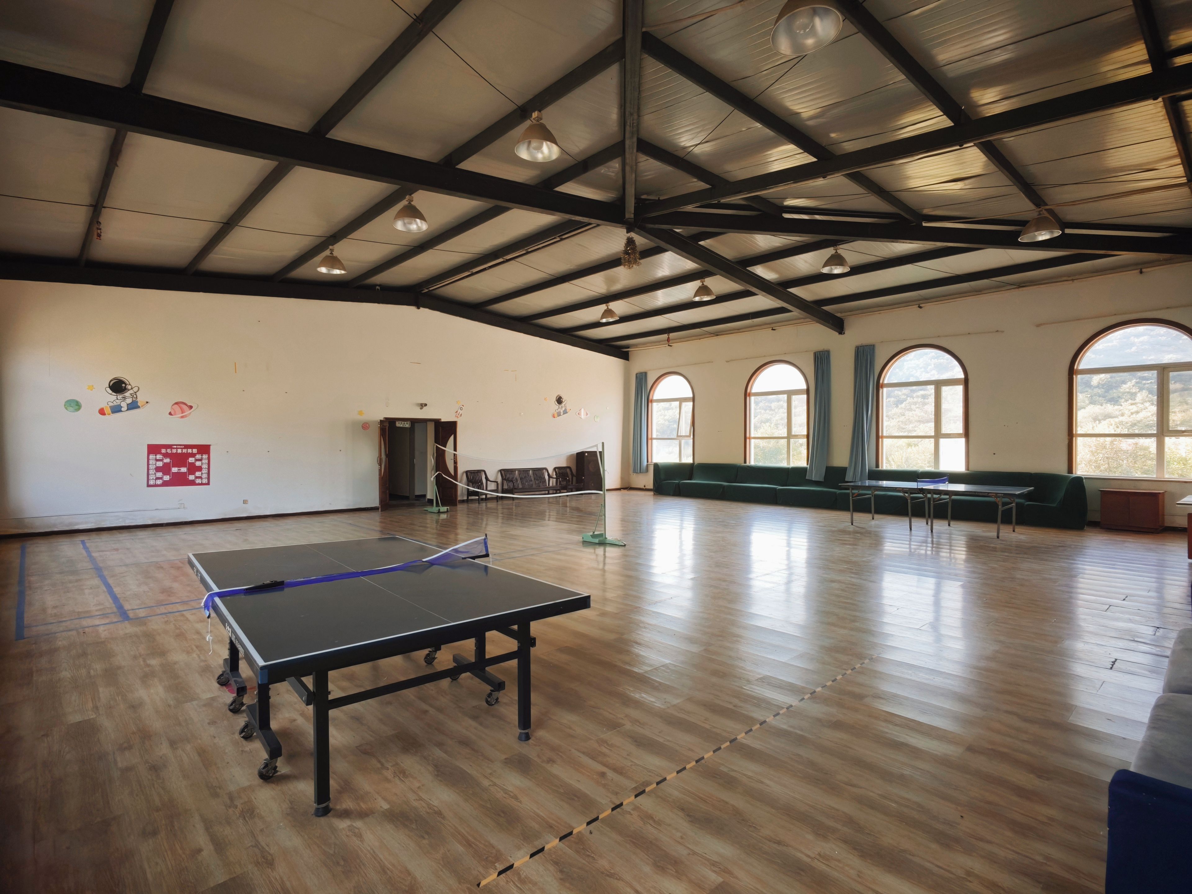 A spacious indoor area with a ping pong table, seating, and large windows.