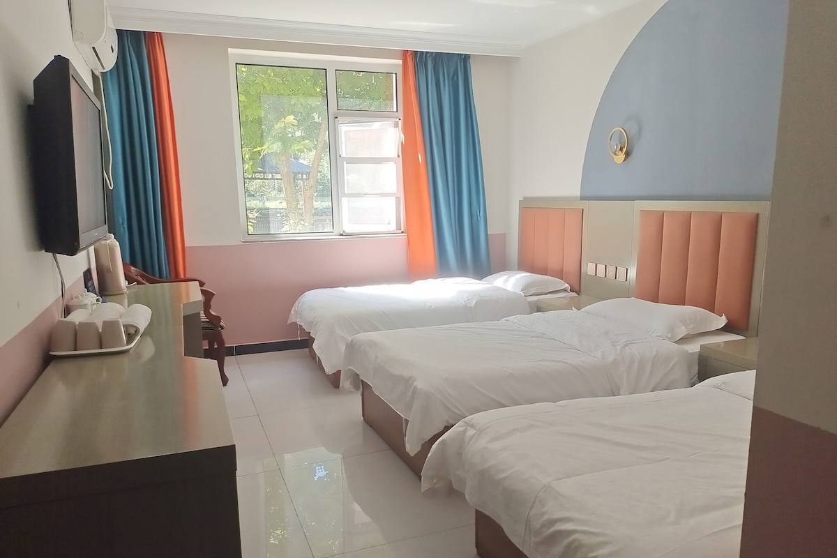 A hotel room with two beds, a desk with a telephone, and a window with curtains.