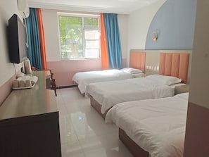 Habitación de hotel con dos camas, un escritorio con teléfono y una ventana con cortinas.