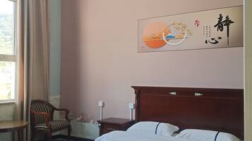A hotel room with a bed, a chair, a nightstand, and a wall with a decorative piece.