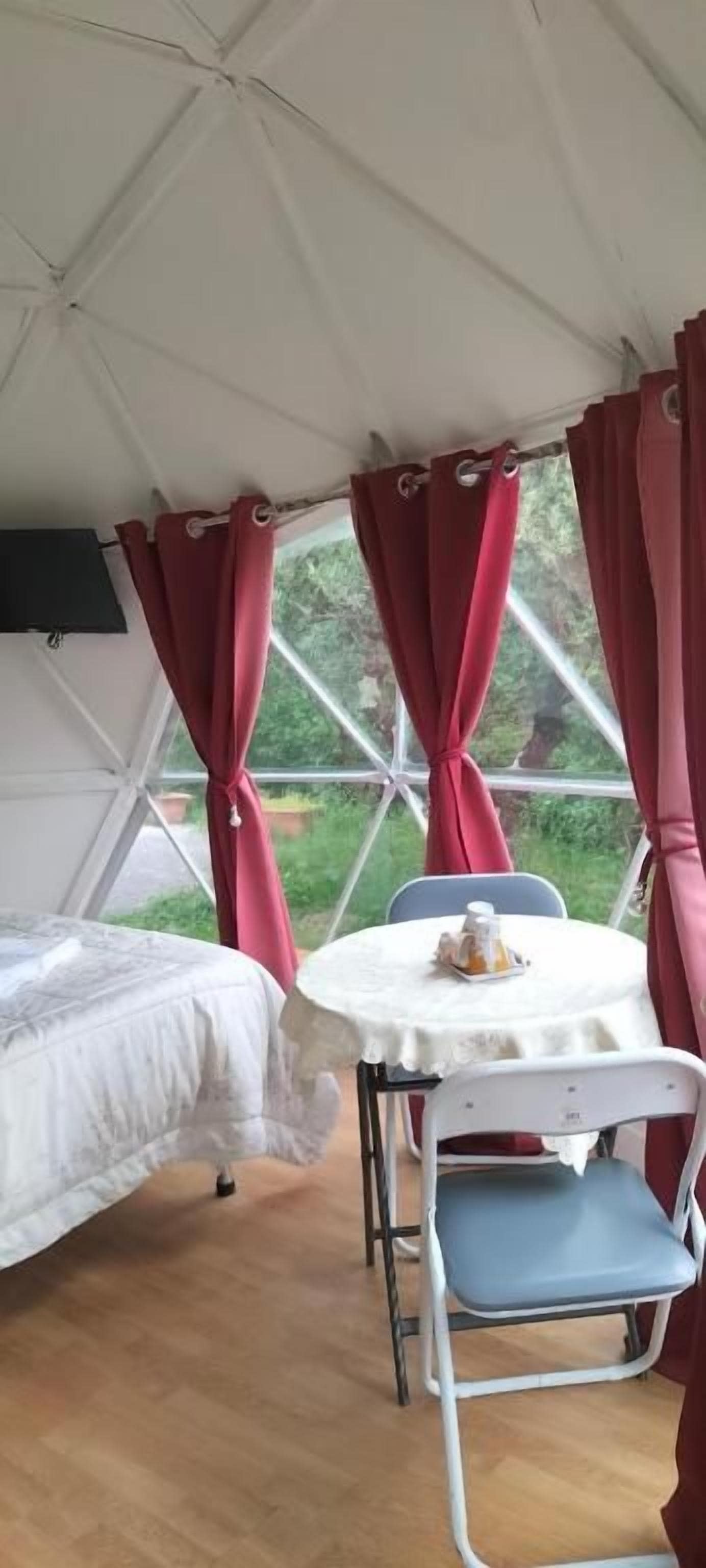 Alojamiento en tienda de campaña con cama, una mesa y una silla, y cortinas.