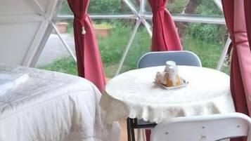 Un alloggio con tende, un letto, un tavolo con una sedia e delle tende.