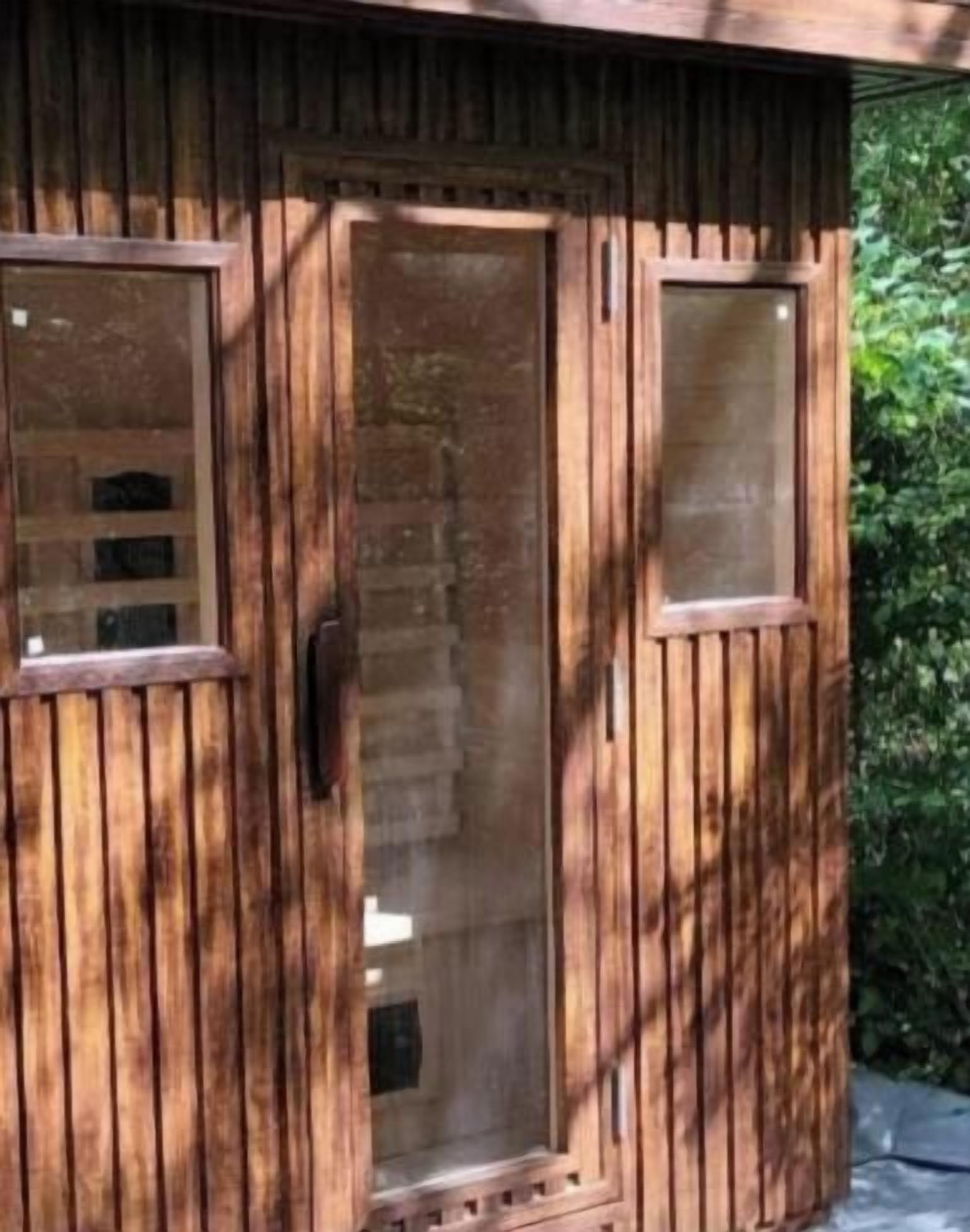 Un edificio de madera con una puerta y dos ventanas.