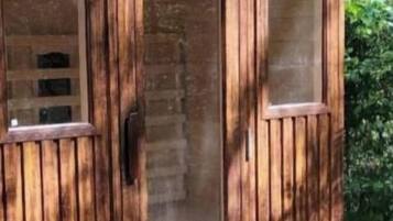 Un edificio de madera con una puerta y dos ventanas.