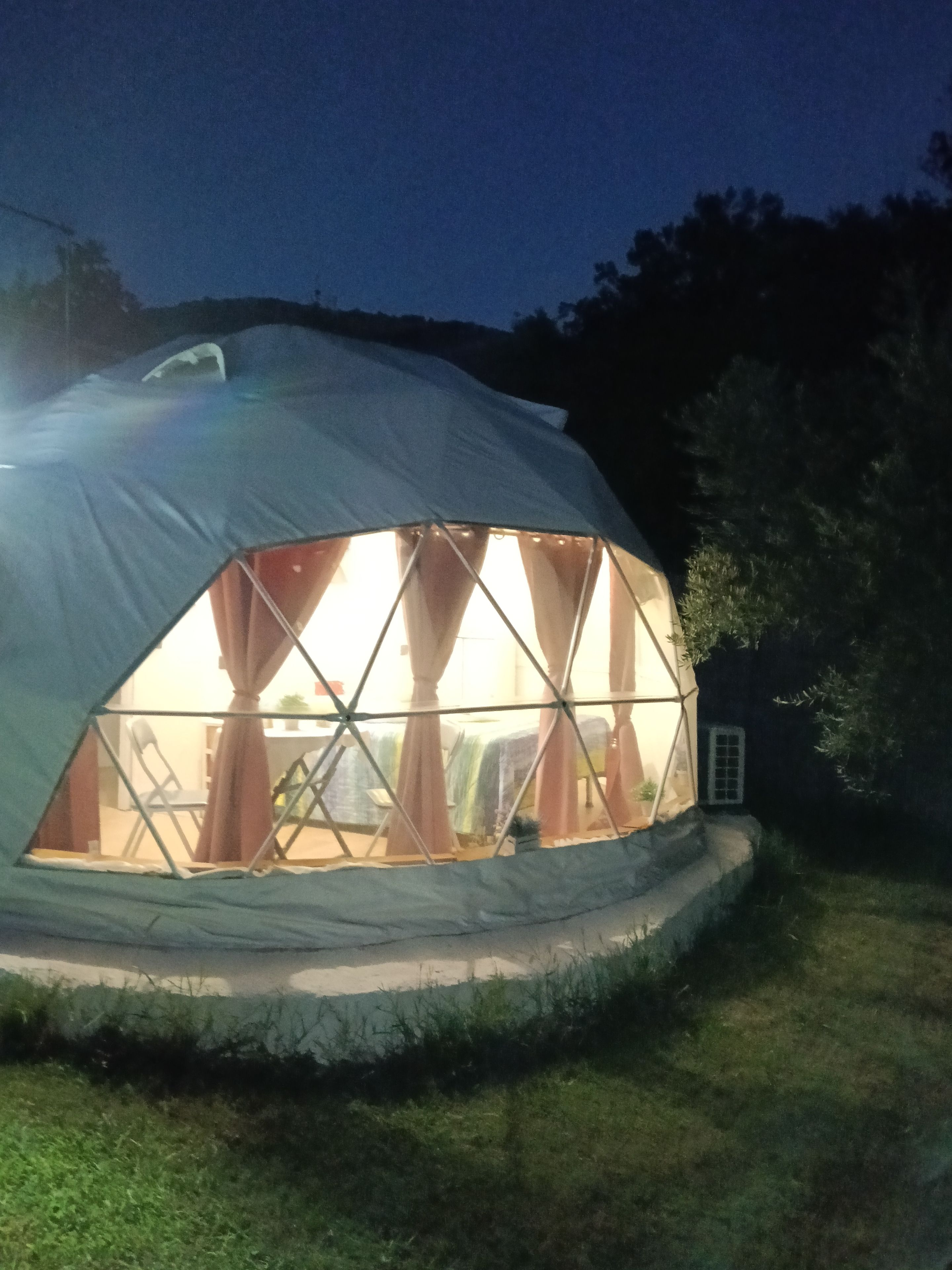Een koepelvormige tent met een raam, omgeven door gras.
