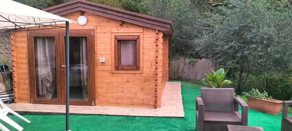 Eine Holzhütte mit einer Schiebetür aus Glas, einem kleinen Fenster und einer Terrasse mit einem Stuhl und einem Blumentopf.
