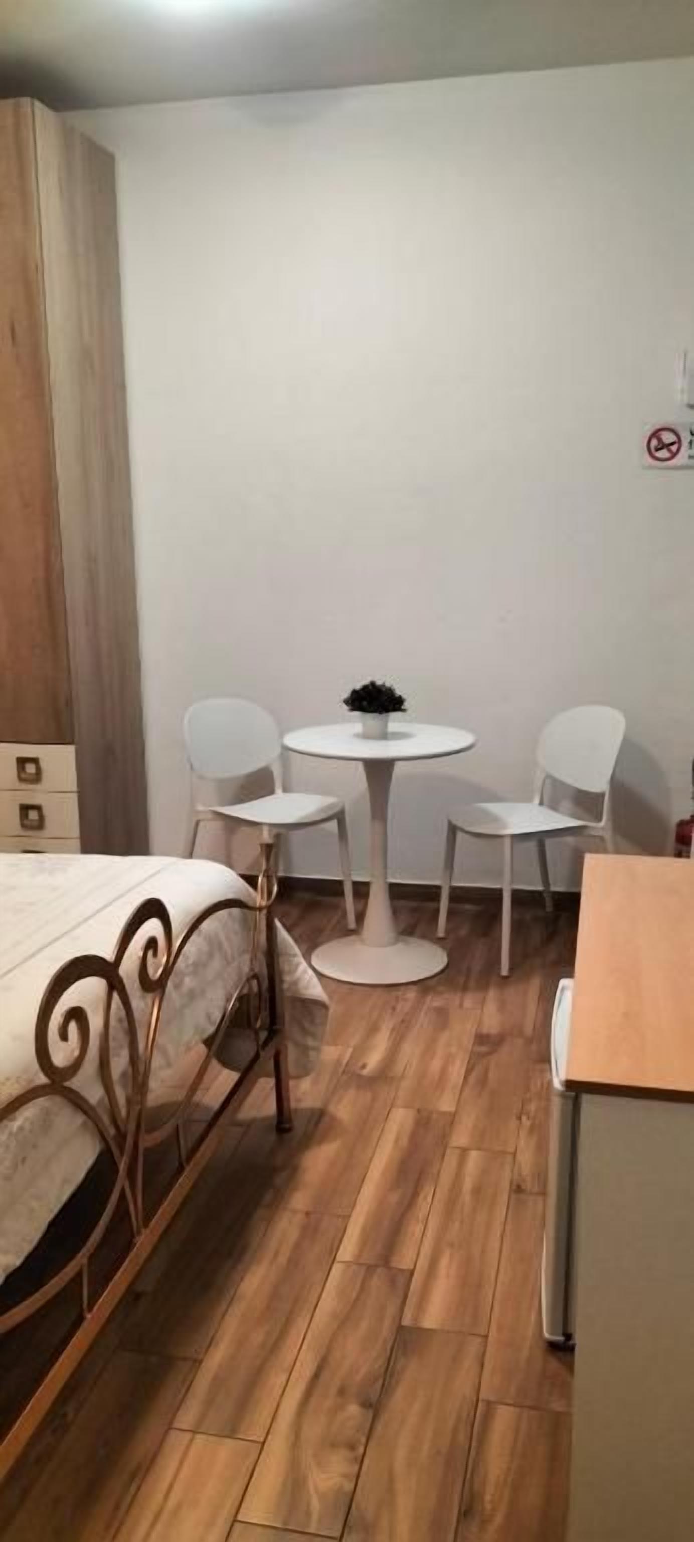 A small room with a bed, a round table with chairs, and a wooden cabinet.