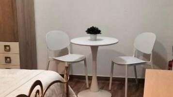 A small room with a bed, a round table with chairs, and a wooden cabinet.