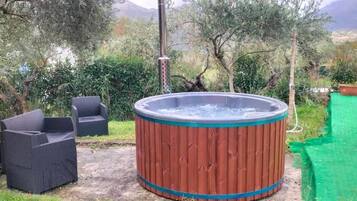 Ein Whirlpool mit Holzverkleidung, umgeben von Pflanzen und Gartenmöbeln.