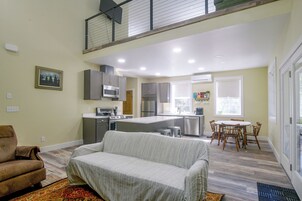 Una cocina moderna con electrodomésticos de acero inoxidable, un comedor con una mesa y sillas de madera, y una sala de estar con un sofá tapizado.