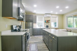 Una cocina moderna con electrodomésticos integrados, una isla grande y un ventanal que proporciona luz natural.