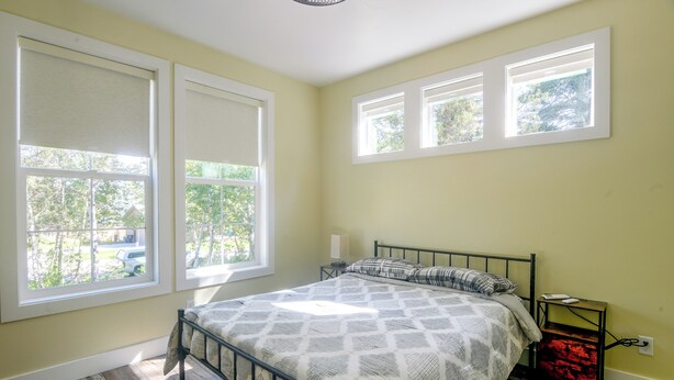 A bedroom with a bed, a nightstand, and a window with a view of trees. - Star Valley Retreat in Alpine Near Snake River (Alpine)