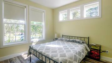 A bedroom with a bed, a nightstand, and a window with a view of trees.