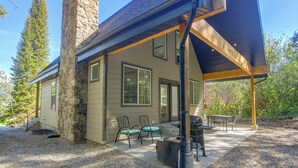 A two-story house with a stone chimney, large windows, and a covered patio area with outdoor furniture. - Star Valley Retreat in Alpine Near Snake River (Alpine)