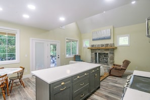 A kitchen with a large island, wooden chairs, a stone fireplace, and a dining table with chairs. - Star Valley Retreat in Alpine Near Snake River (Alpine)
