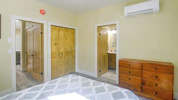 Un dormitorio con cama, cómoda, armario y unidad de aire acondicionado.