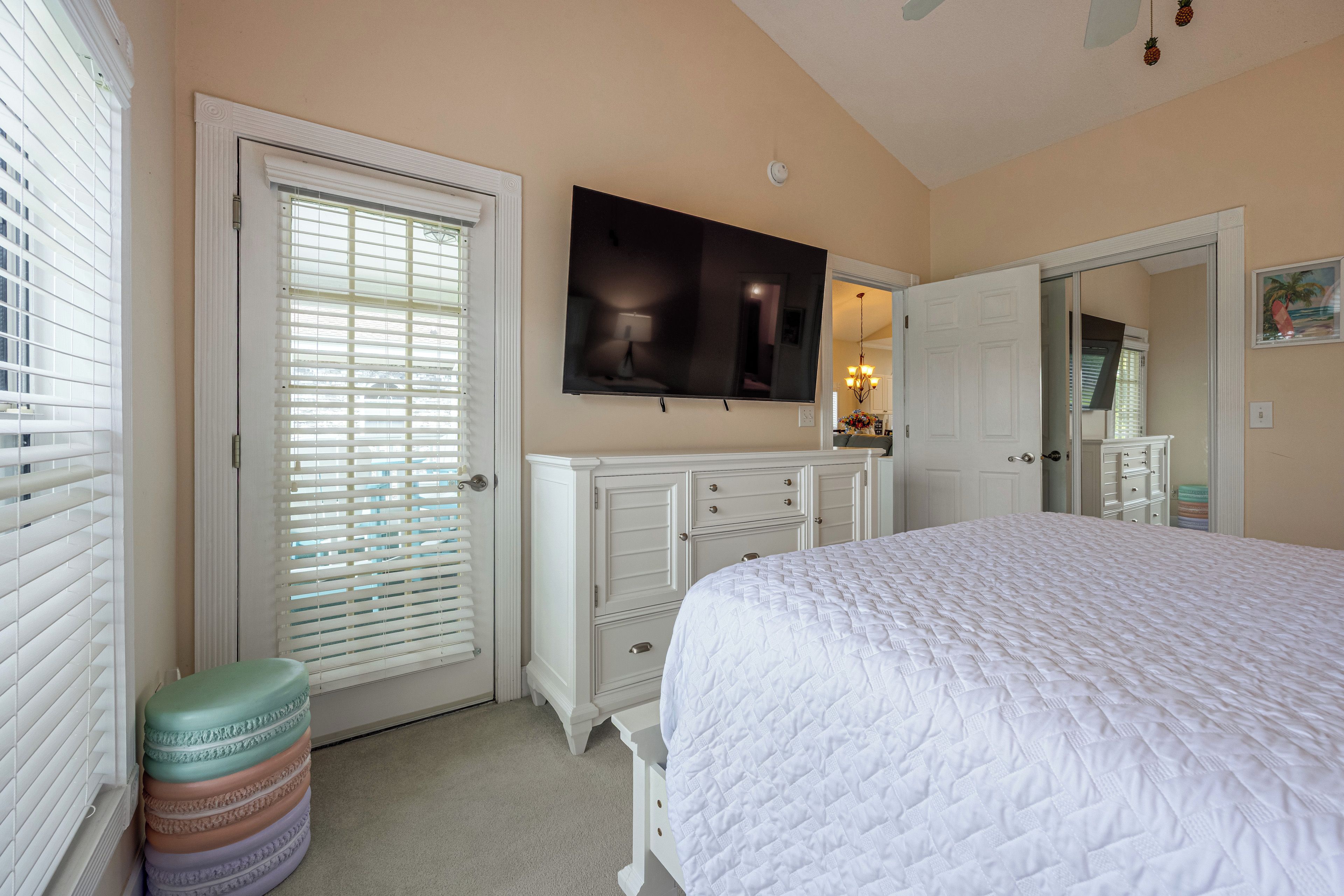 A bedroom with a bed, a television, a dresser, and a door.