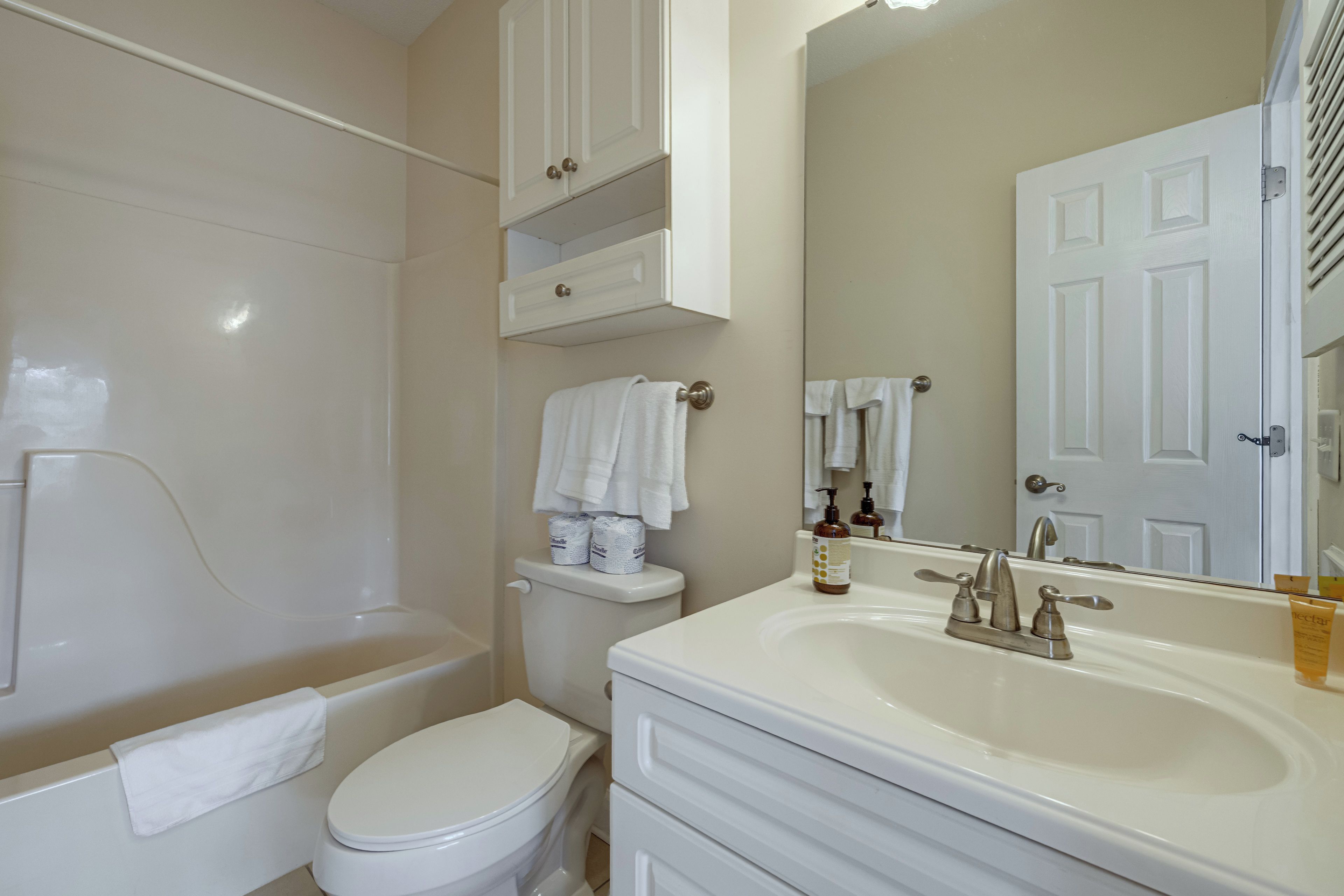 A bathroom with a toilet, a sink, a mirror, and a shower area.