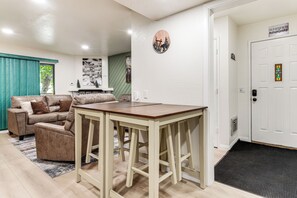 A living room with a sofa, a coffee table, and a door with a doormat. - Walkable Condo Near Ski Shuttle & Mammoth Creek! (Mammoth Lakes)
