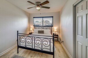 Ein Schlafzimmer mit einem Bett, einem Deckenventilator, einem Fenster mit Jalousien und zwei Nachttischlampen.
