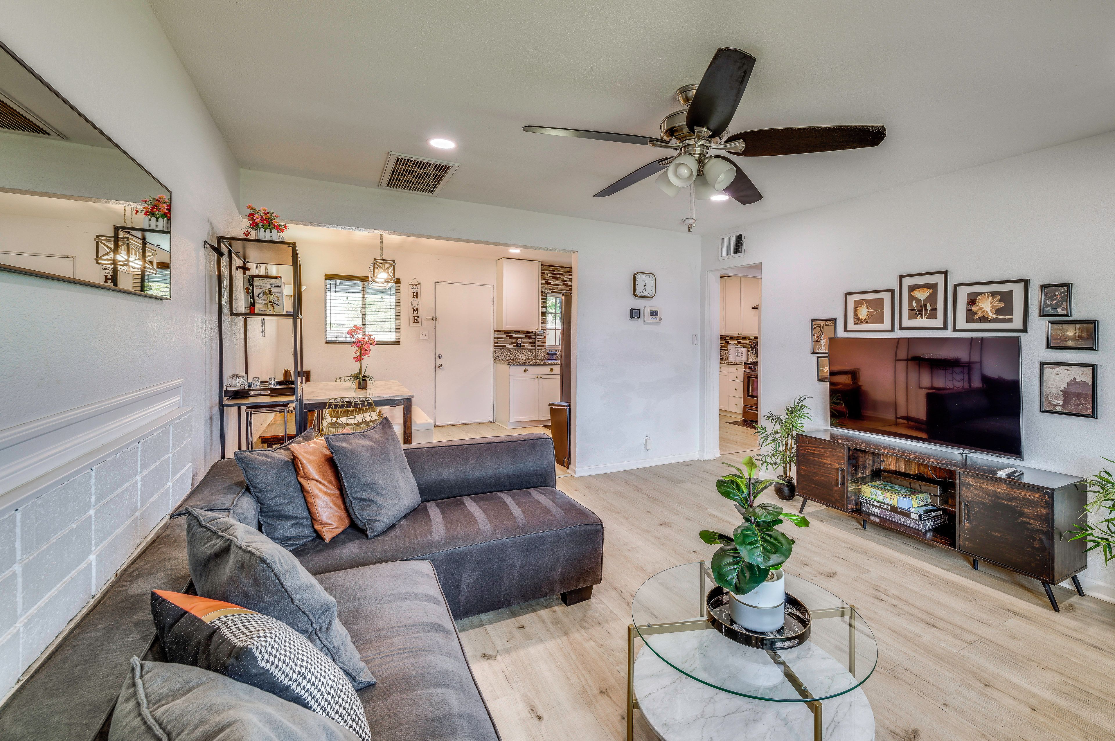 A modern living room with a sectional sofa, a glass coffee table, and a flat-screen TV.