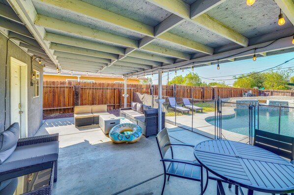 A covered patio with outdoor furniture, a pool, and a wooden fence. - 5 Mi to Empire Polo Club! Poolside Group Getaway (Indio)