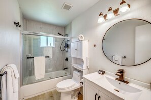 Une salle de bain moderne avec une douche à parois de verre, des toilettes, un lavabo avec un miroir et un porte-serviettes.