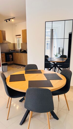 Un espace repas moderne avec une table ronde en bois, des chaises noires et une grande fenêtre offrant une belle vue.