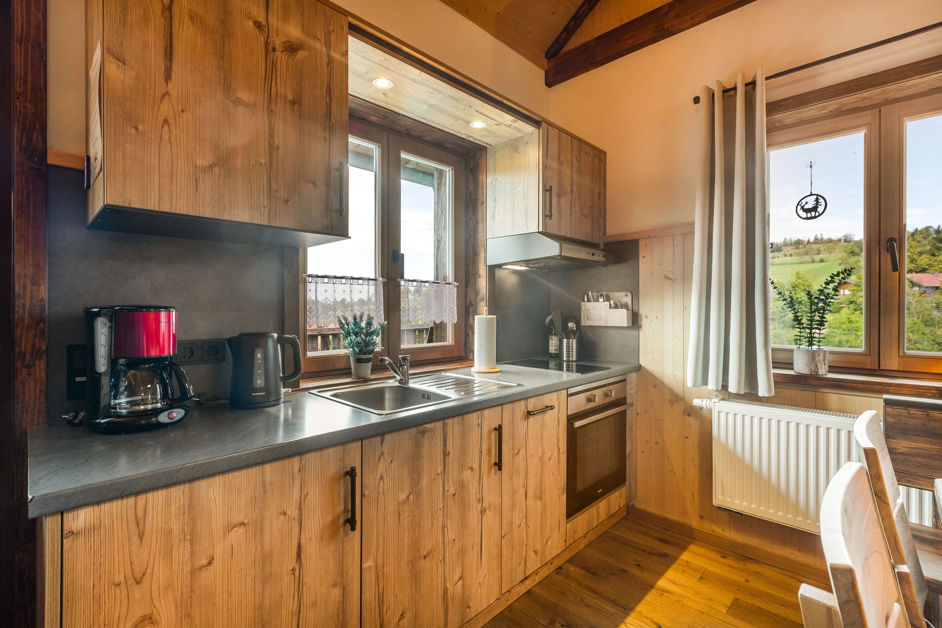 A kitchen with wooden cabinets, a stainless steel sink, and a window with a view of the outdoors.