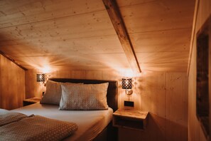 Ein gemütliches Schlafzimmer in einer Holzhütte mit einem Bett, Kissen und zwei Wandlampen.