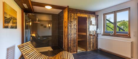 A modern bathroom with a glass-enclosed shower, wooden accents, and a view of greenery outside.