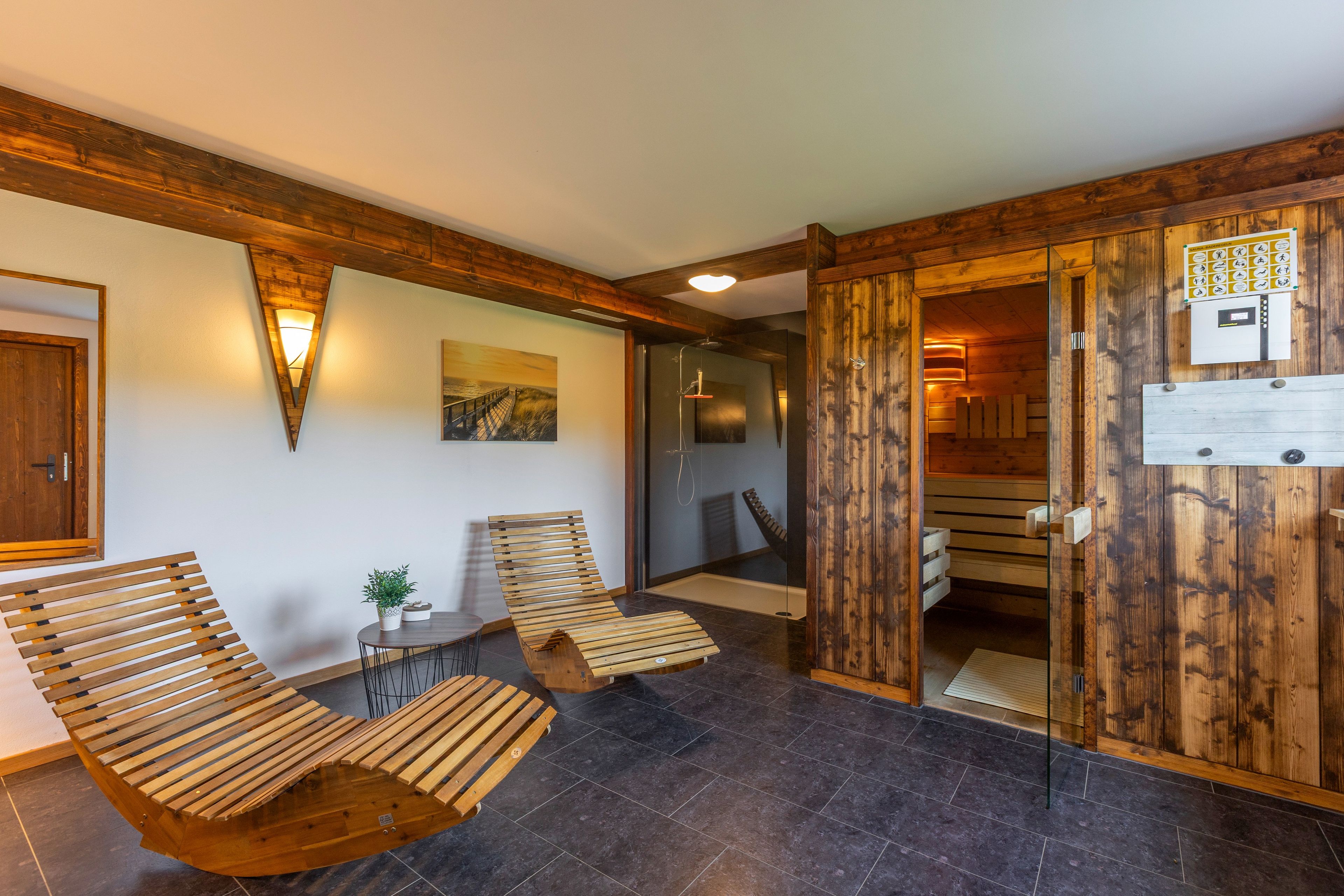 A wooden interior with a bench, a table, and a door leading to a sauna area.
