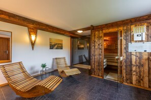 A wooden interior with a bench, a table, and a door leading to a sauna area.