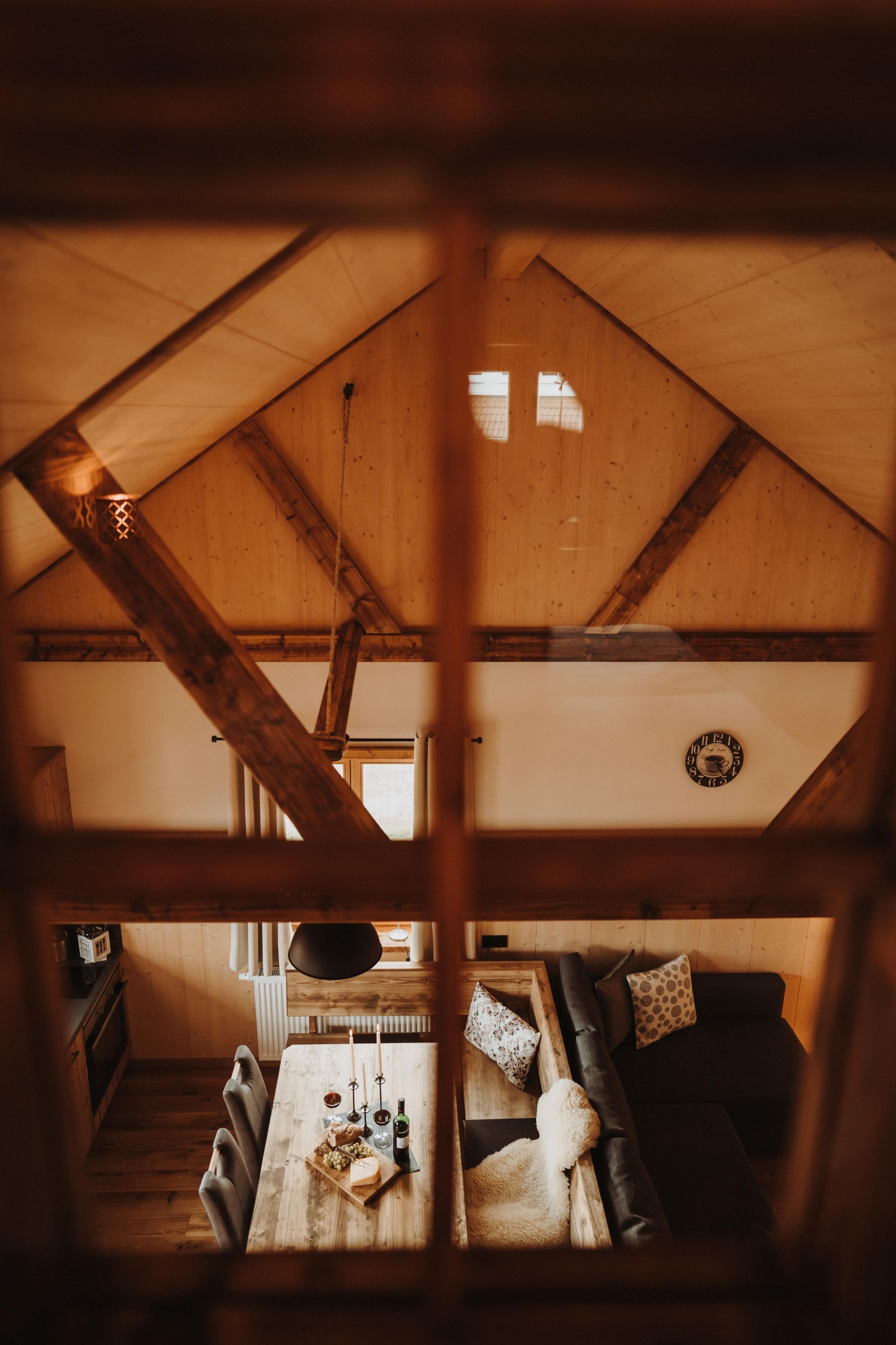 Un intérieur chaleureux avec un plafond en bois, une table à manger décorée de bougies et un canapé agrémenté de coussins.