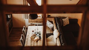 Un interno accogliente con soffitto in legno, un tavolo da pranzo con candele e un divano con cuscini.