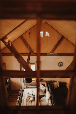 Ein gemütliches Interieur mit Holzbalkendecke, einem Esstisch mit Kerzen und einer Couch mit Kissen.
