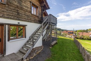 A wooden house with a wooden staircase leading to a deck. - Chalet “Oberwald 1” with Private Terrace, Garden, Sauna, Wi-Fi, and Parking (Schotten)