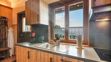 Eine Küche mit Holzschränken, einer Edelstahl-Spüle, einer Kaffeemaschine und einem Fenster mit Aussicht.