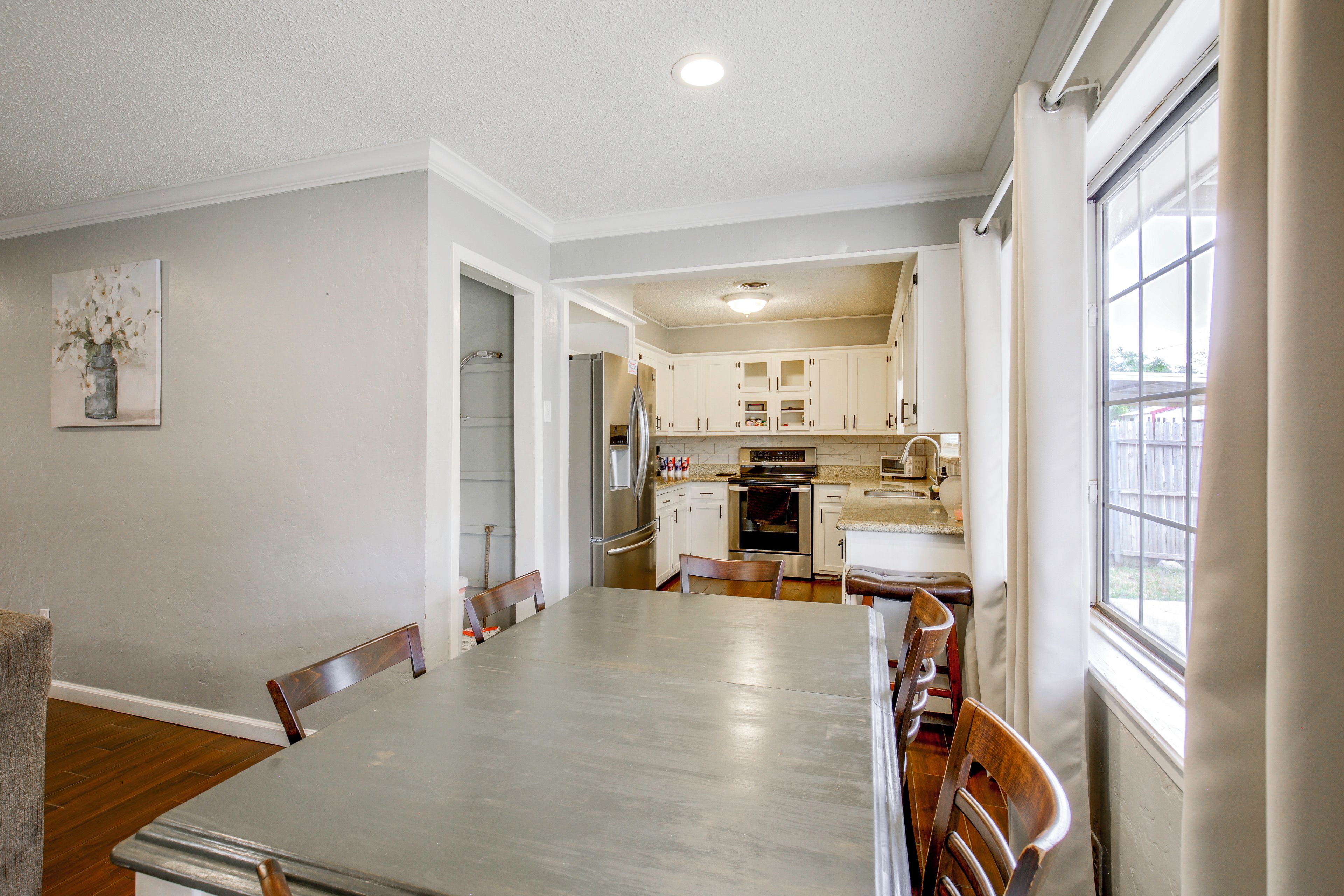 A modern kitchen with white cabinets, stainless steel appliances, and a dining area with a large table and chairs.