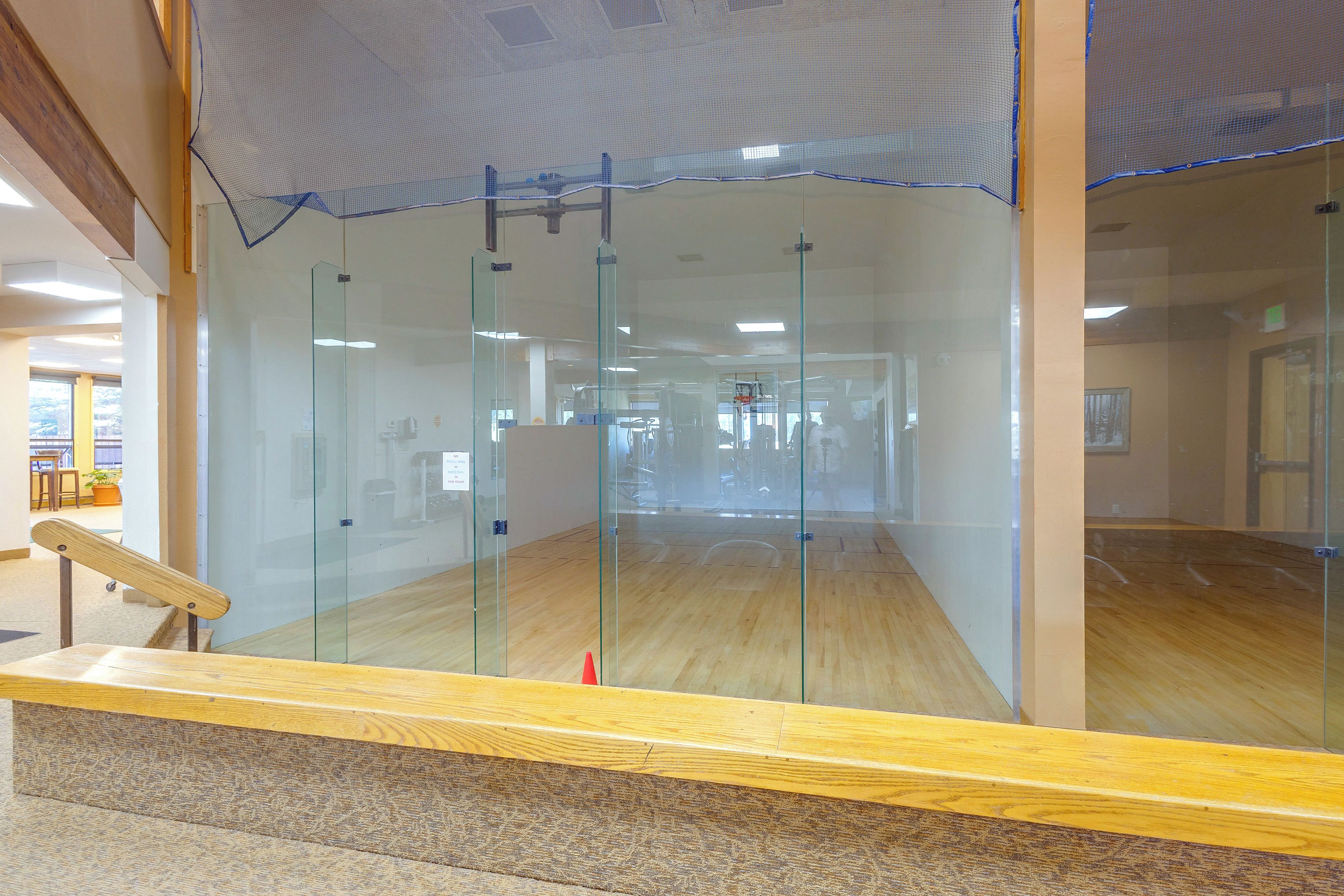 A glass-walled room with a wooden floor, a bench, and a door.