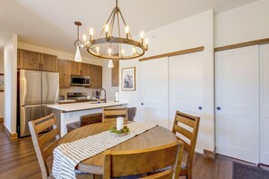 A modern kitchen with wooden cabinets, stainless steel appliances, and a chandelier. - Ski, Bike & Explore Winter Park! Modern Condo (Fraser)