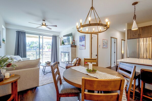 A modern living room with a dining area, large windows, and a fireplace. - Ski, Bike & Explore Winter Park! Modern Condo (Fraser)