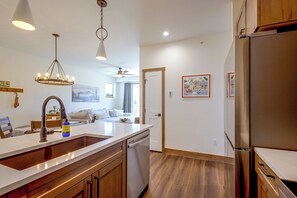 A modern kitchen with a central island, wooden cabinets, and a stainless steel refrigerator. - Ski, Bike & Explore Winter Park! Modern Condo (Fraser)