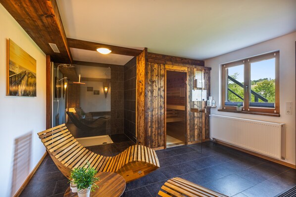 A modern bathroom with a glass-enclosed shower, wooden accents, and a view of greenery outside. - Chalet "Oberwald 3" with Private Terrace, Garden, Sauna, Wi-Fi, and Parking (Schotten)
