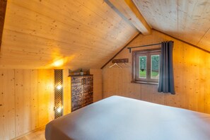 Et soveværelse med træloft, seng, garderobeskab og et vindue med gardiner.