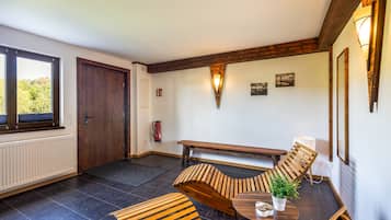 A room with a wooden bench, a round table with a potted plant, and a fire extinguisher mounted on the wall.